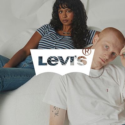 Un uomo è seduto in primo piano e si tocca la testa. Una donna è appoggiata con disinvoltura su una poltrona sullo sfondo. Il logo Levi's è posizionato sopra l'immagine.