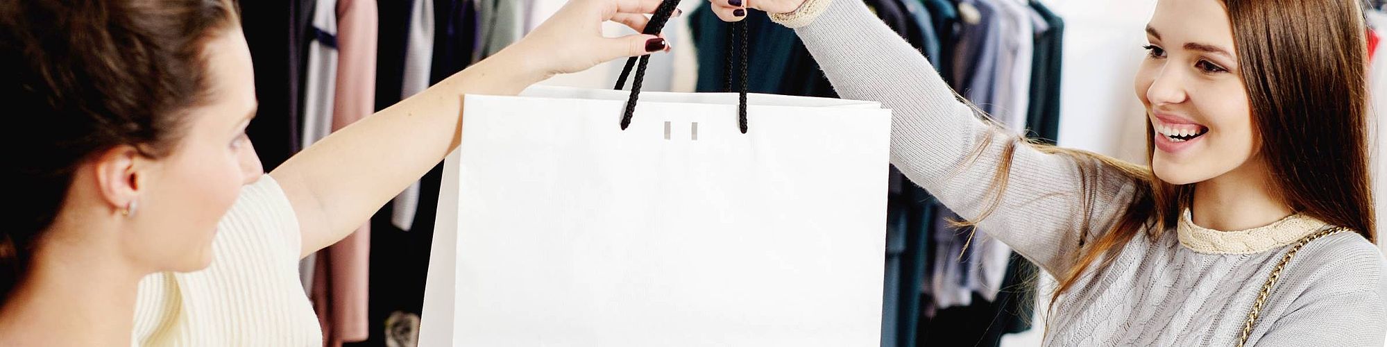 Una donna consegna una busta della spesa a un'altra donna.