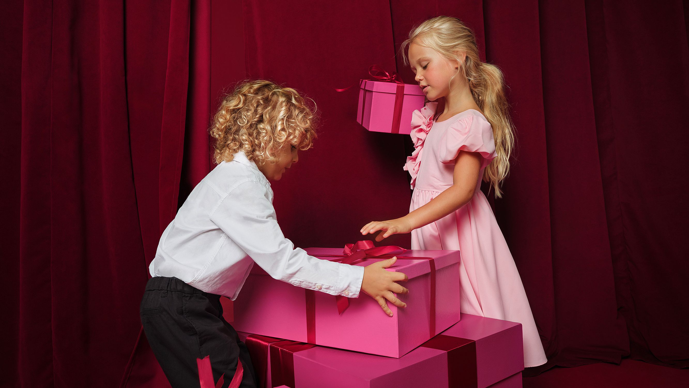 Un bambino e una bambina giocano con delle scatole regalo. 